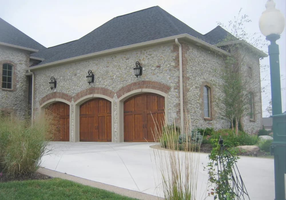 Arched wood carriage garage doors on a stone three-car garage