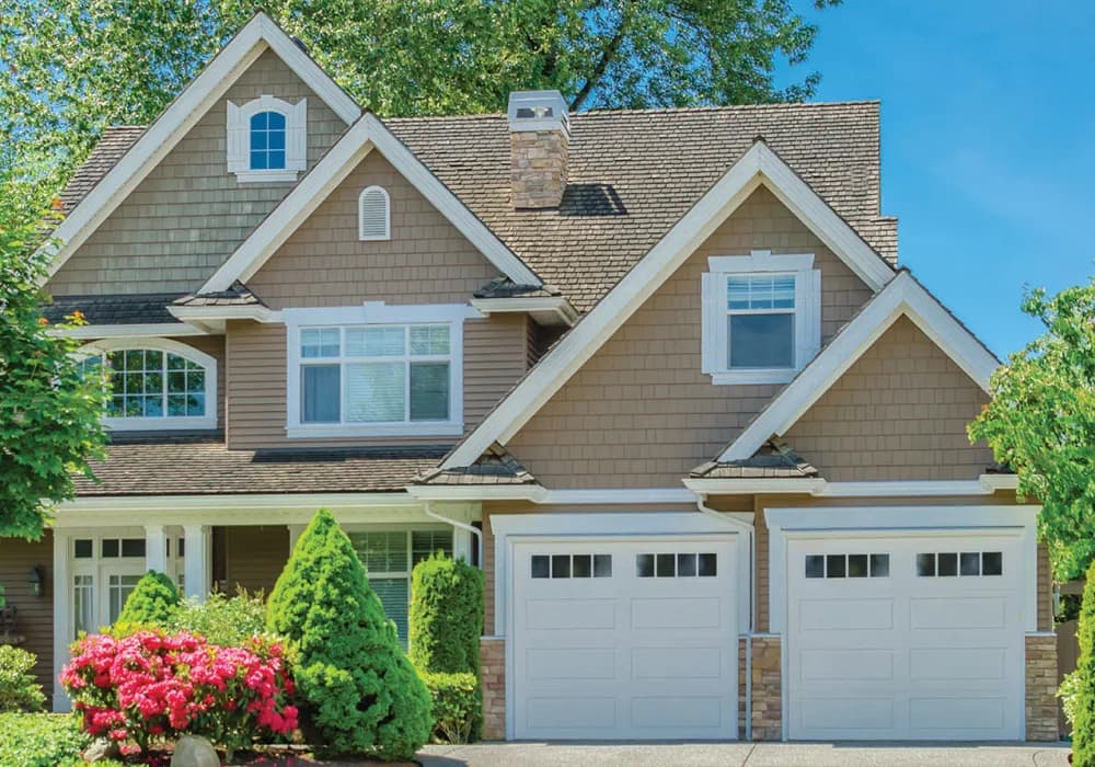 Two white garage doors with window tops on a craftsman-style home