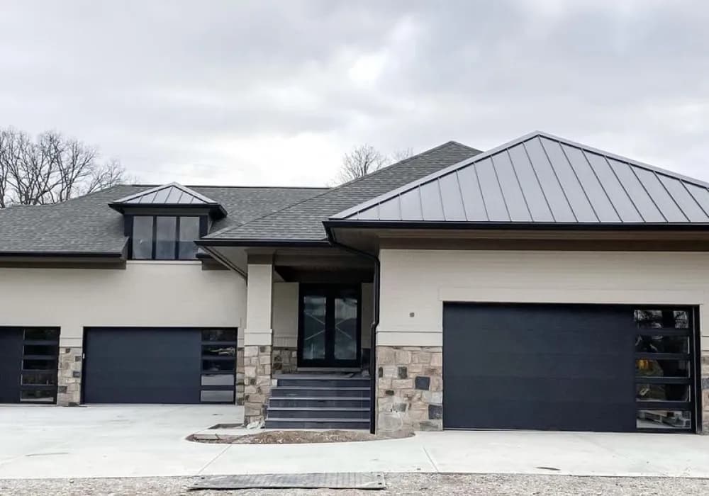 Black flush-panel garage doors on a modern single-story home with a standing-seam roof